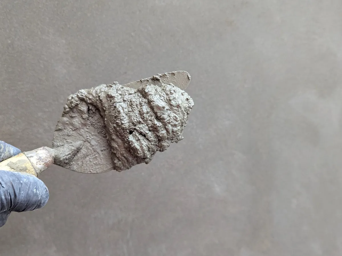 Truelle chargée d'enduit appliquée sur un mur