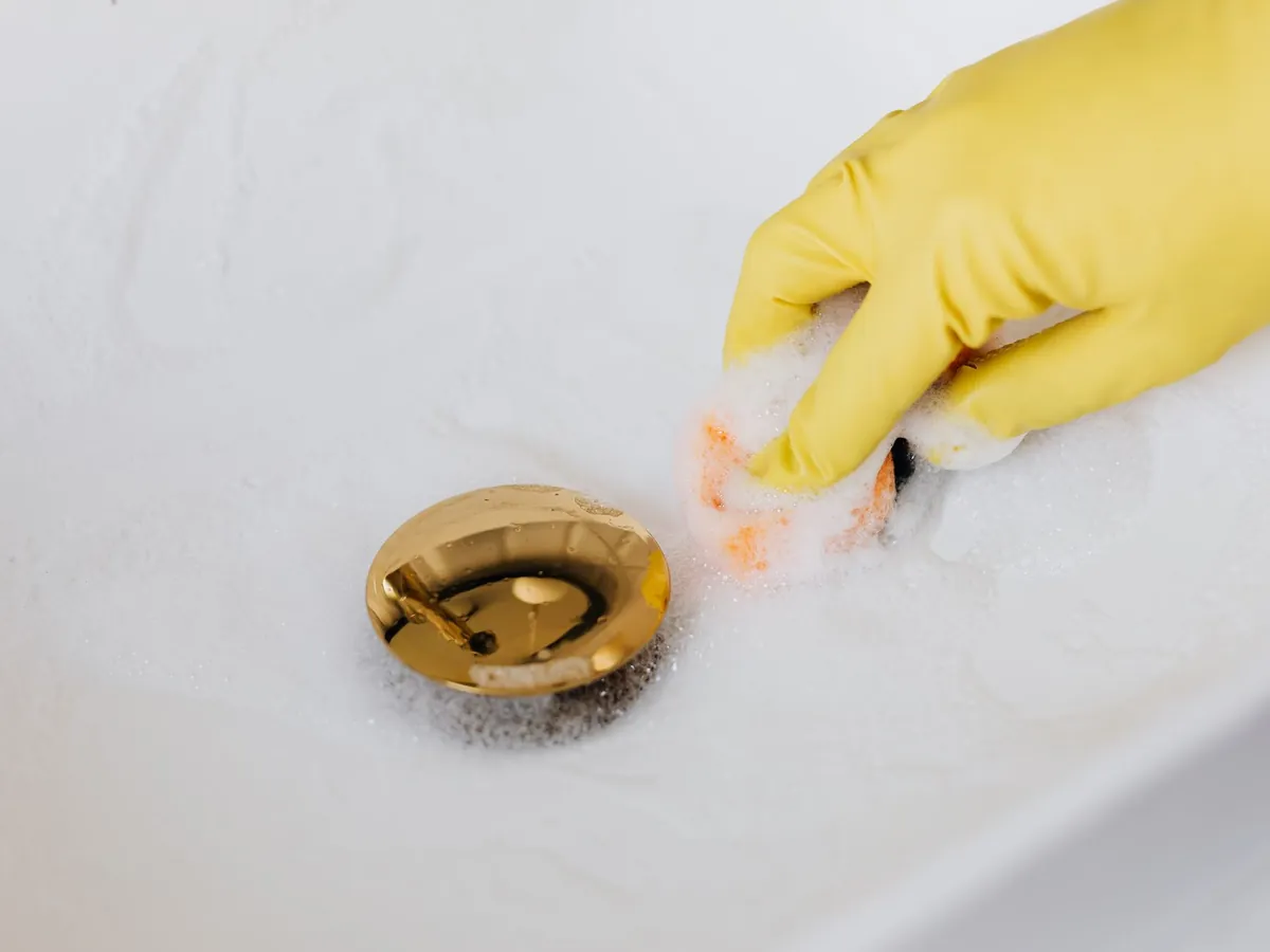 Main gantée qui nettoie la bonde d'un lavabo bouché