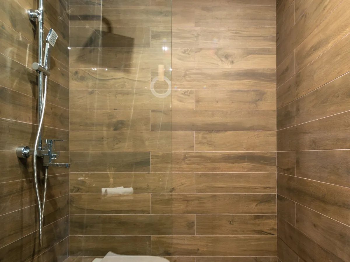 Douche à l'italienne carrelée en imitation bois avec paroi vitrée
