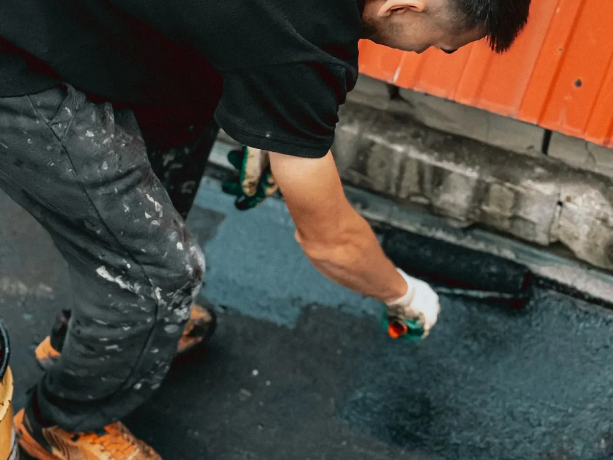 Ouvrier qui passe un produit d'étanchéité au rouleau sur un toit-terrasse