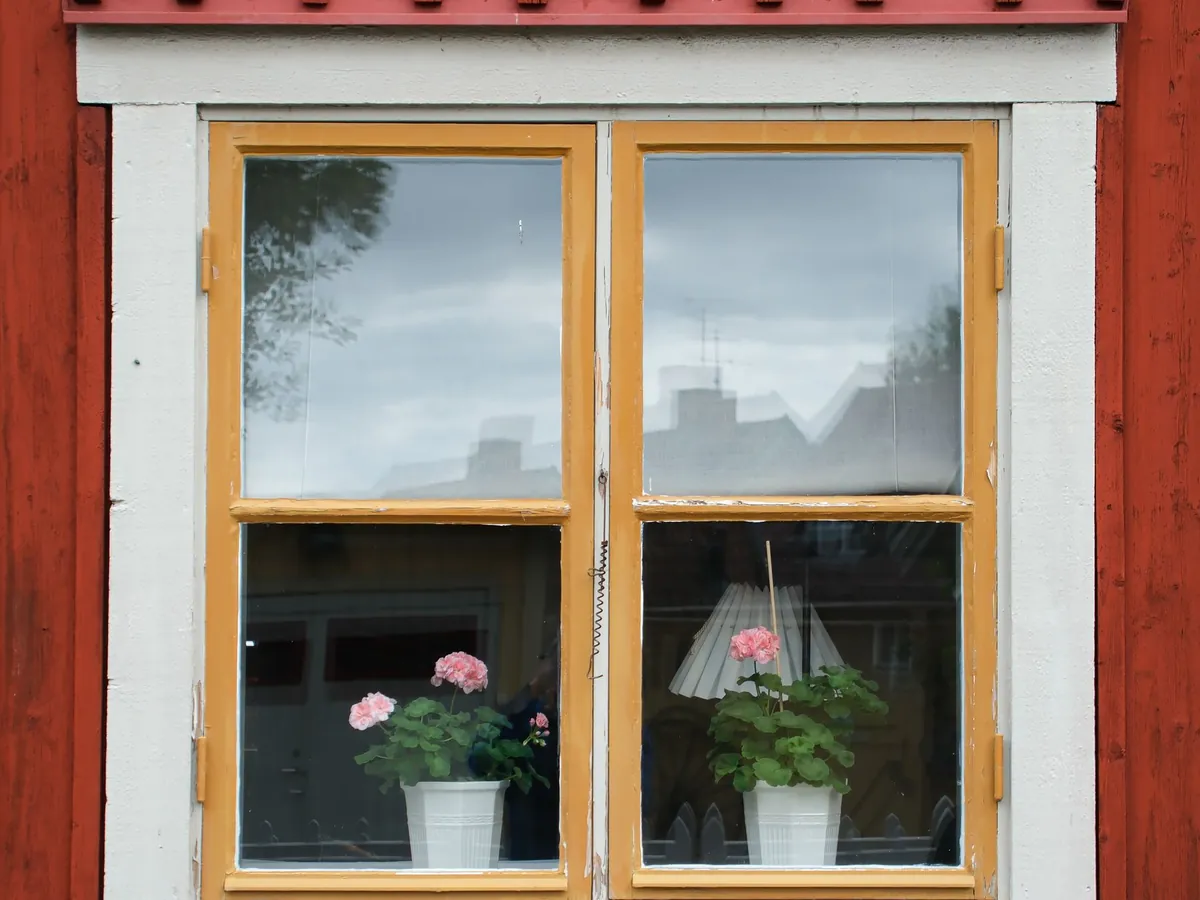 Fenêtre en bois à deux vantaux sur une façade rouge