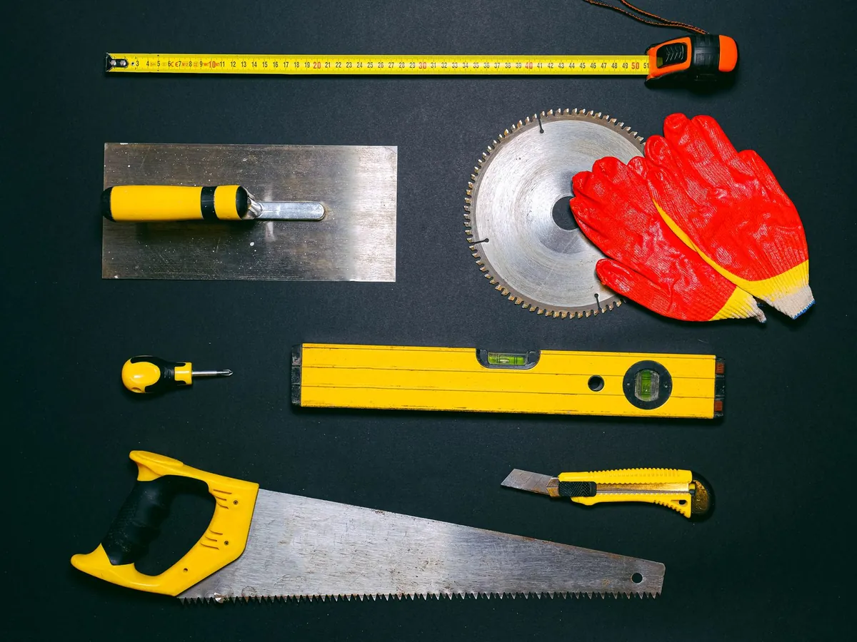 Outils de chantier alignés : scie, niveau, mètre et gants