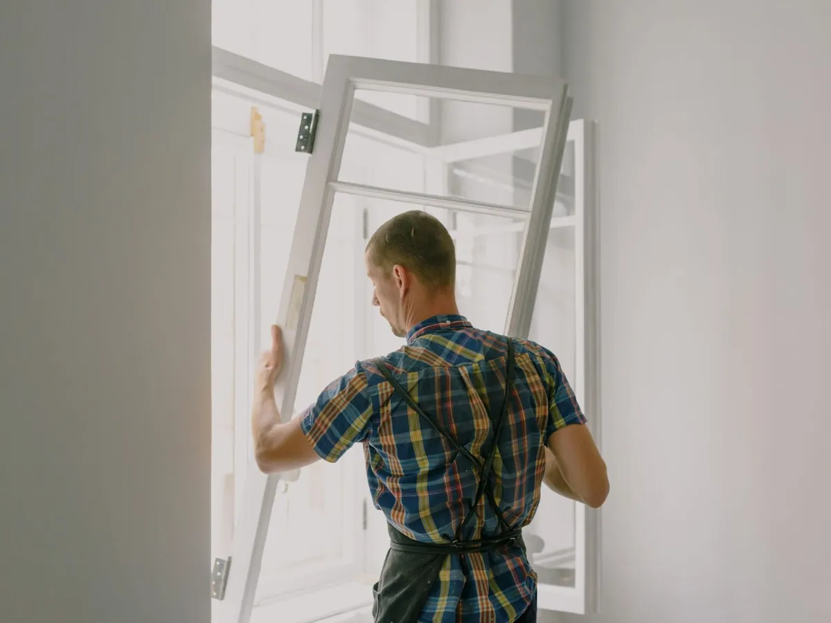 Artisan qui met en place un châssis de fenêtre dans une pièce en travaux