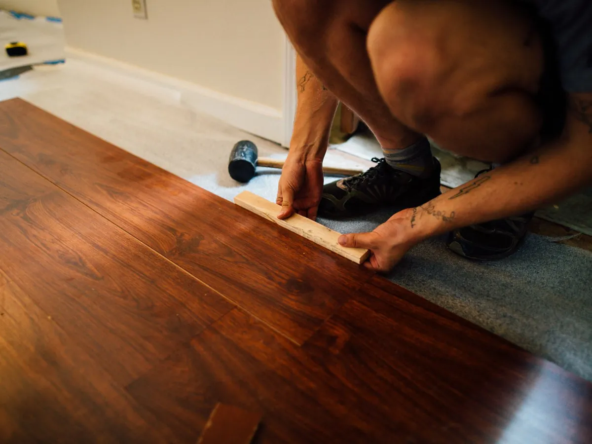 Artisan qui emboîte des lames de parquet sur le sol