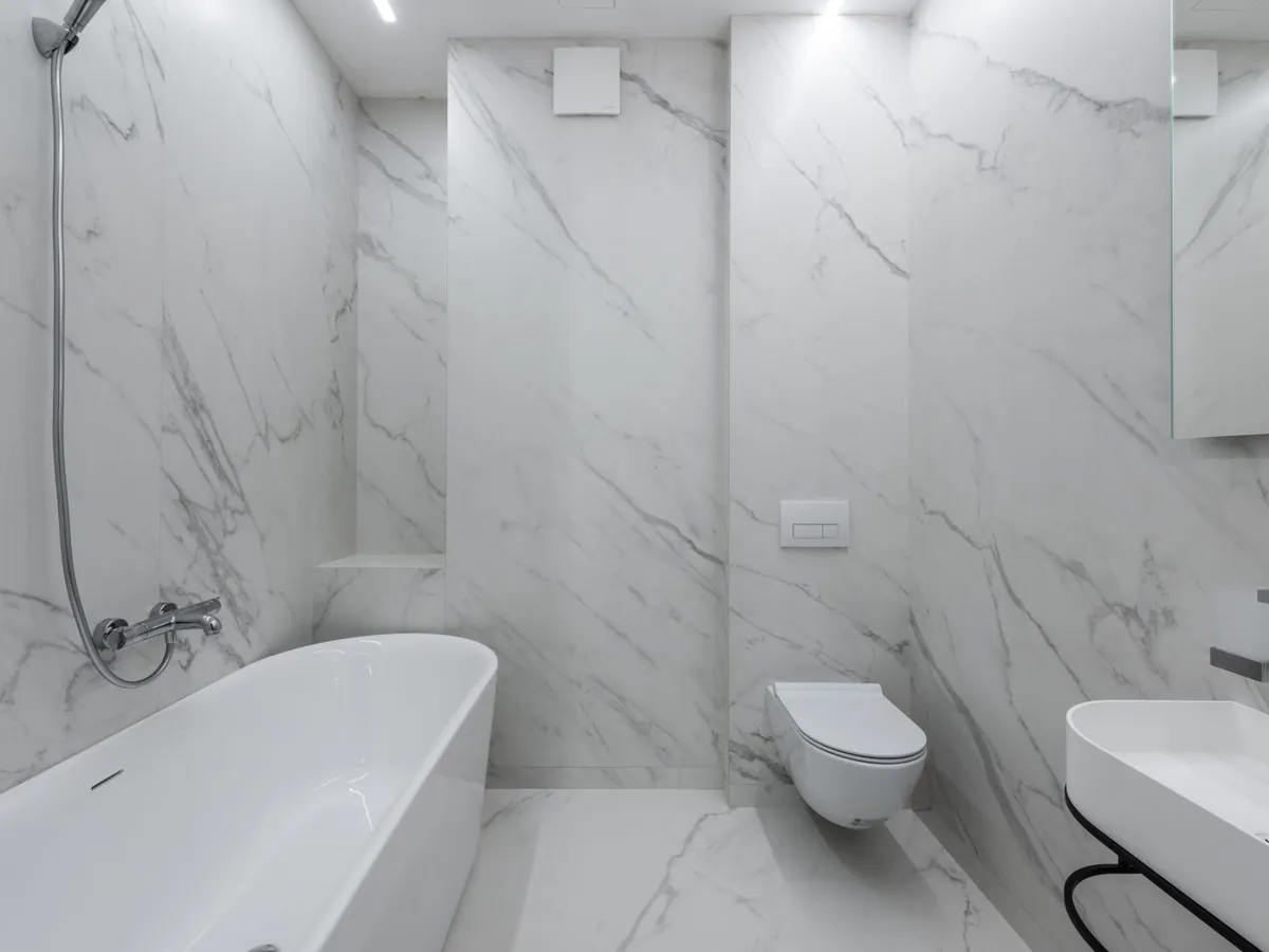 Salle de bain en marbre blanc avec WC suspendu, baignoire et lavabo