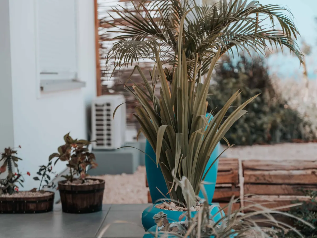 Unité extérieure de climatisation au fond d'une terrasse plantée
